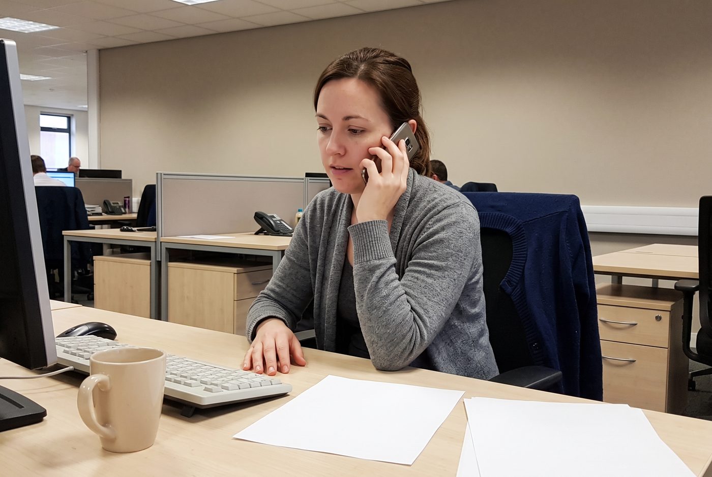 A woman taking a phone call at her desk at work