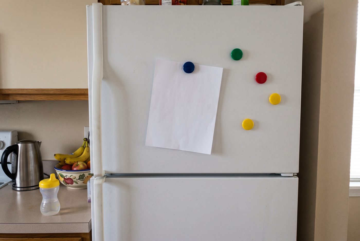 A single sheet of paper held by a magnet on a fridge door