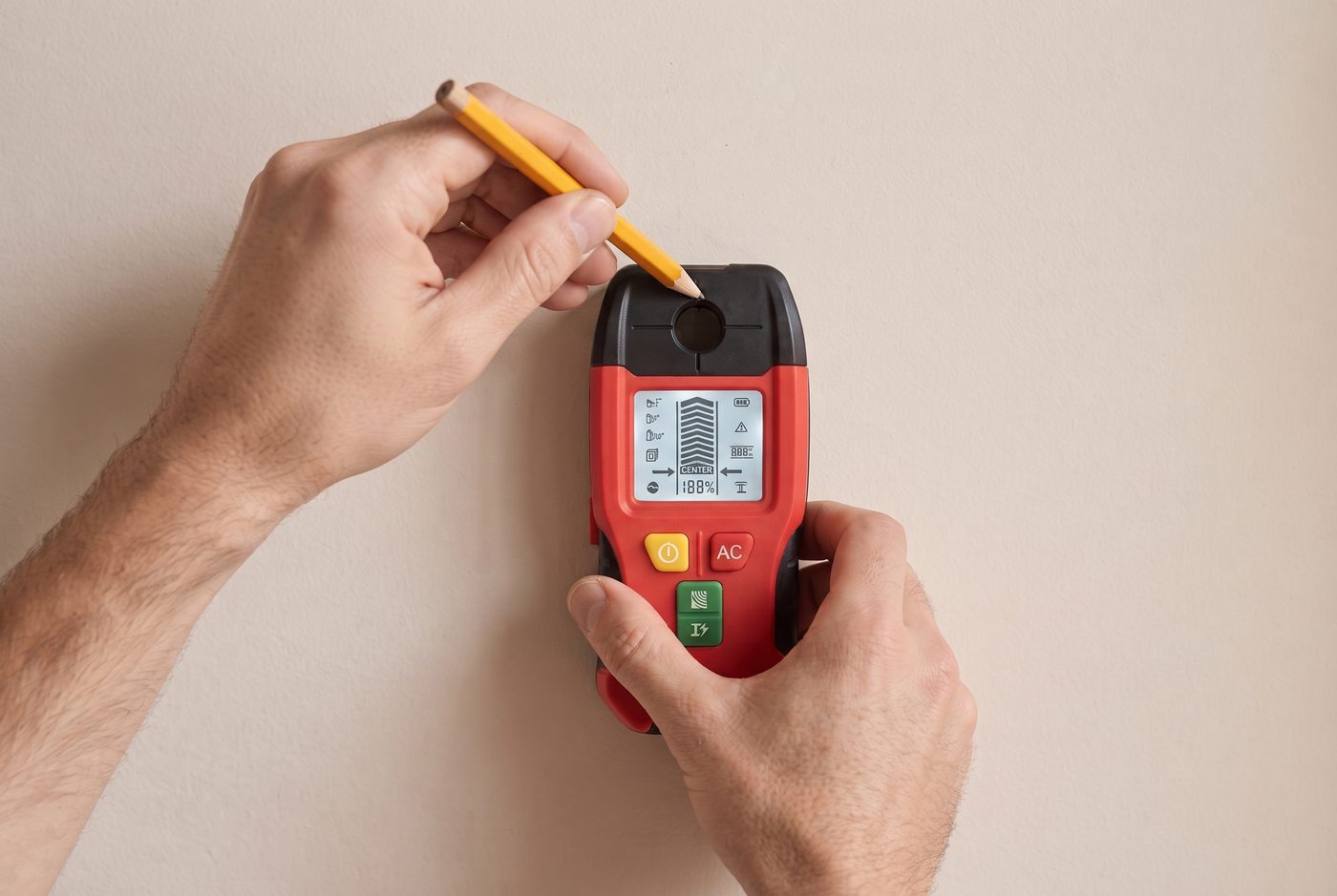 A pencil marking the wall through the centre hole of the Wallux wall scanner